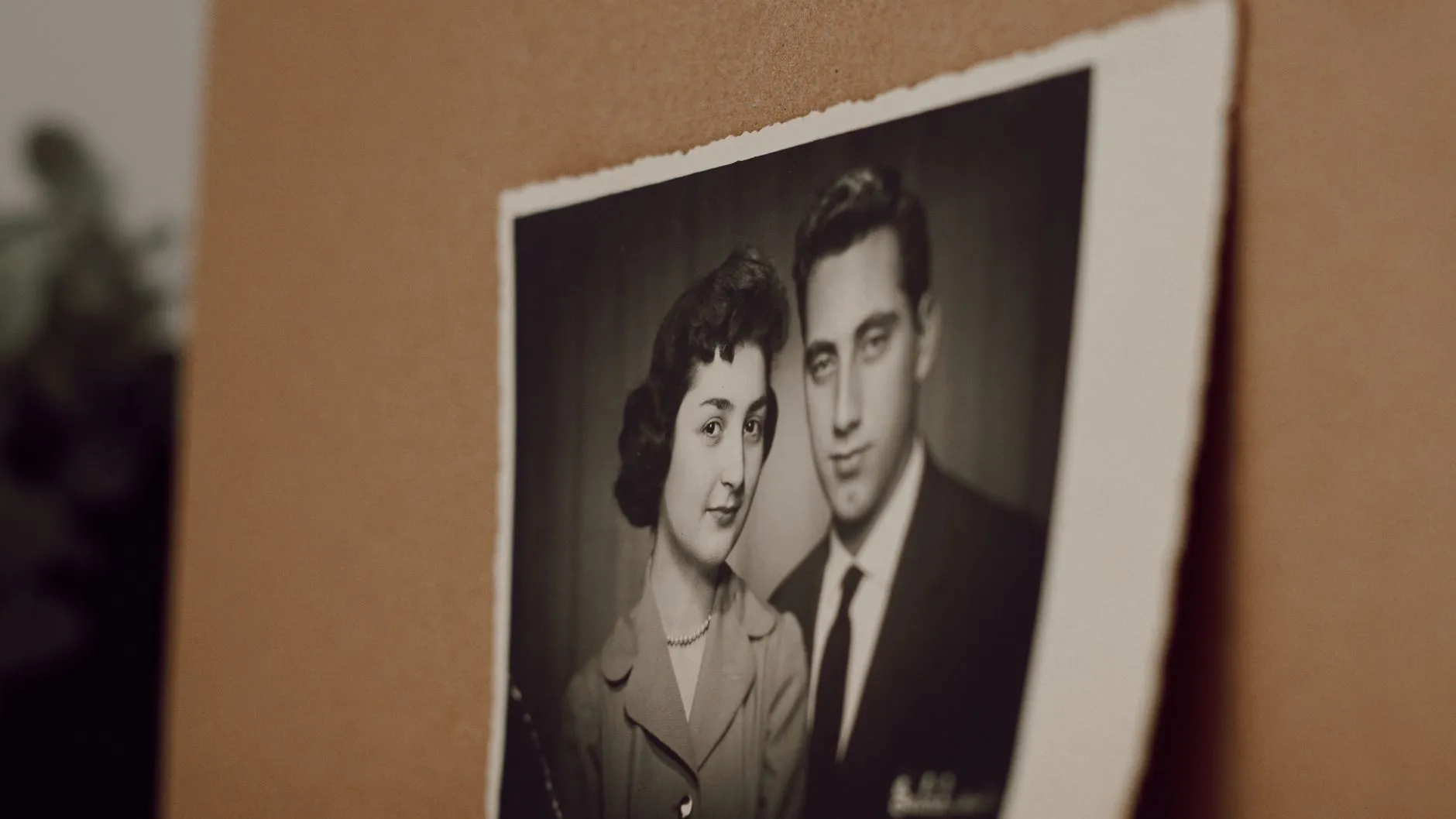 A black and white studio portrait of a young couple from the 1950s, printed on paper and pinned to a corkboard