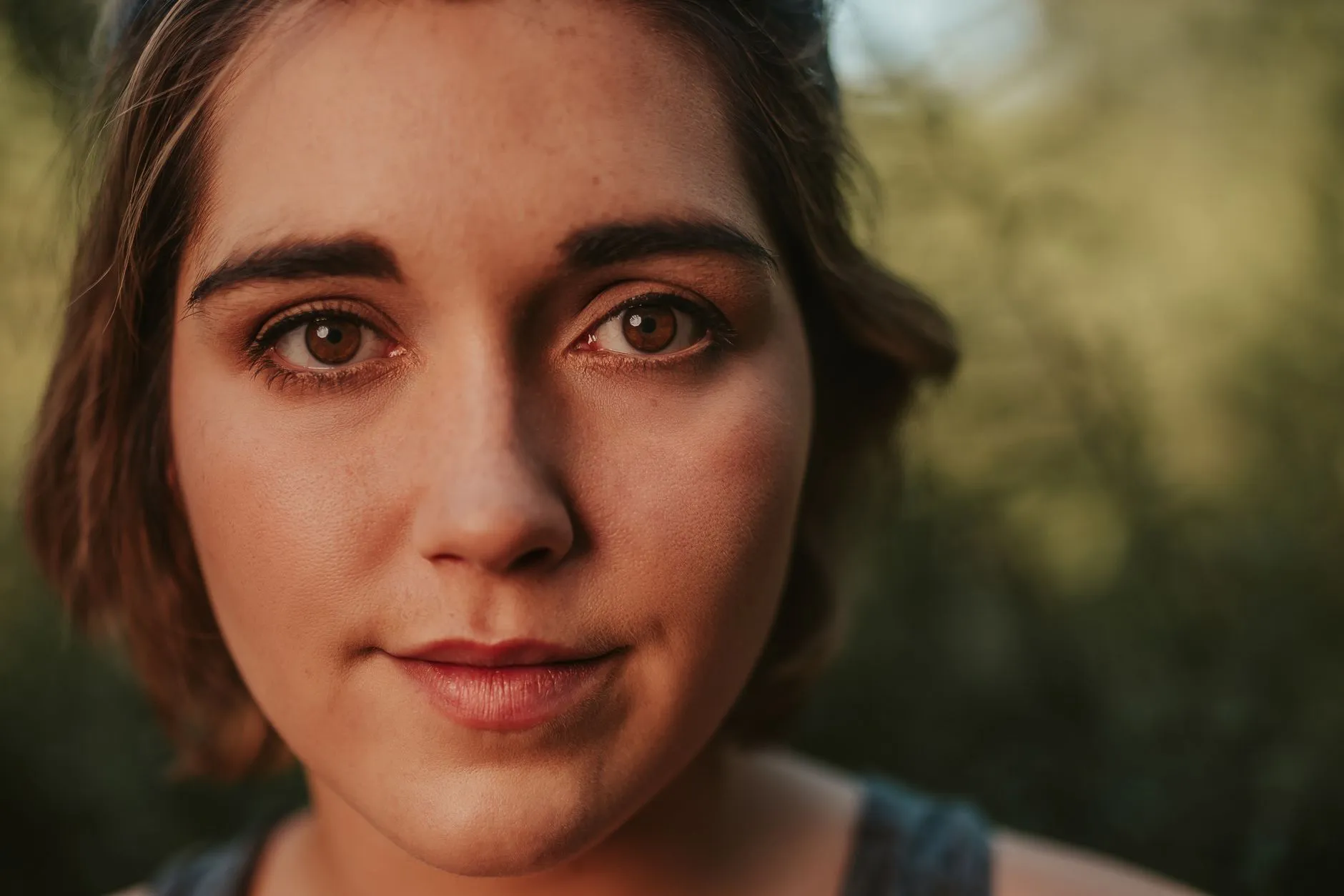 Extreme close up of a woman's eyes and upper face in soft outdoor light, sharp enough to see individual lashes